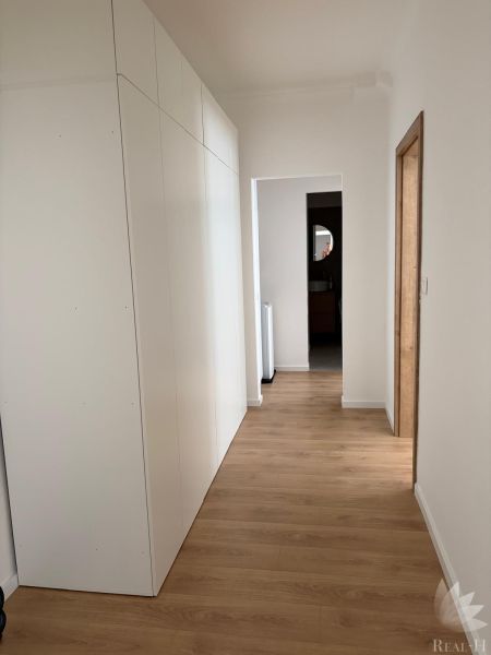 Interior of a 3-room apartment with white cabinets and a floor with a wood decor.