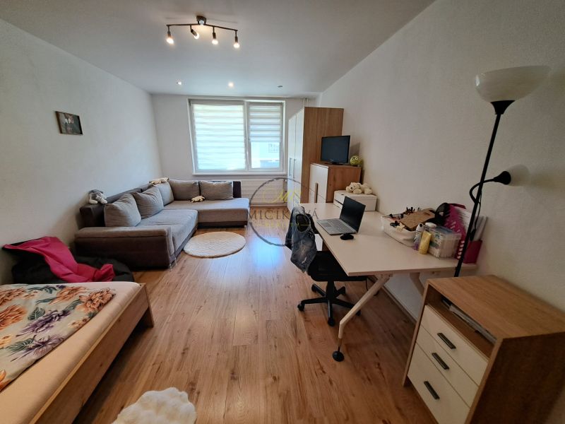 Living room in a 3-room apartment with a seating area and a desk, floor with wooden decor.