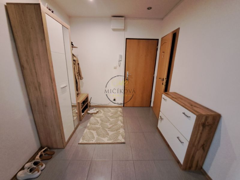 A hallway in a 3-room apartment with wooden decor furniture and a doormat.