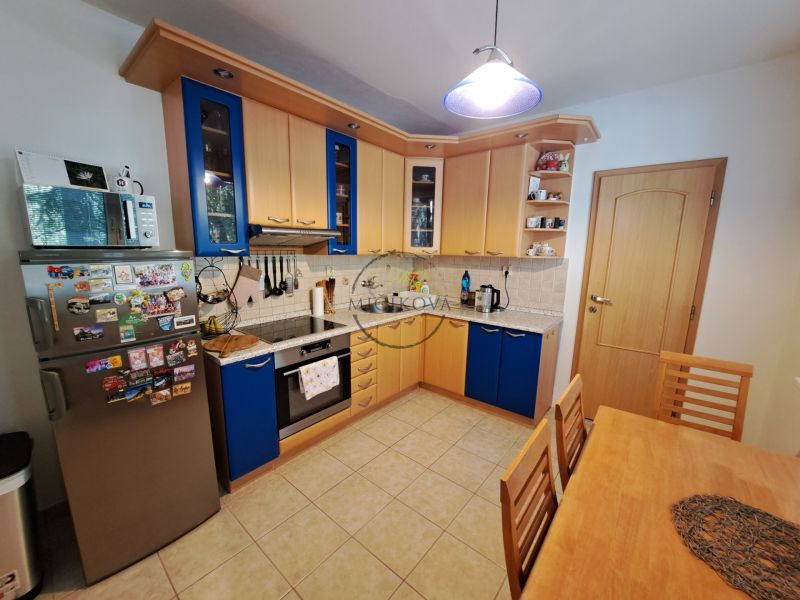 A kitchen in a 3-room apartment with a tiled floor and a wooden kitchen unit.