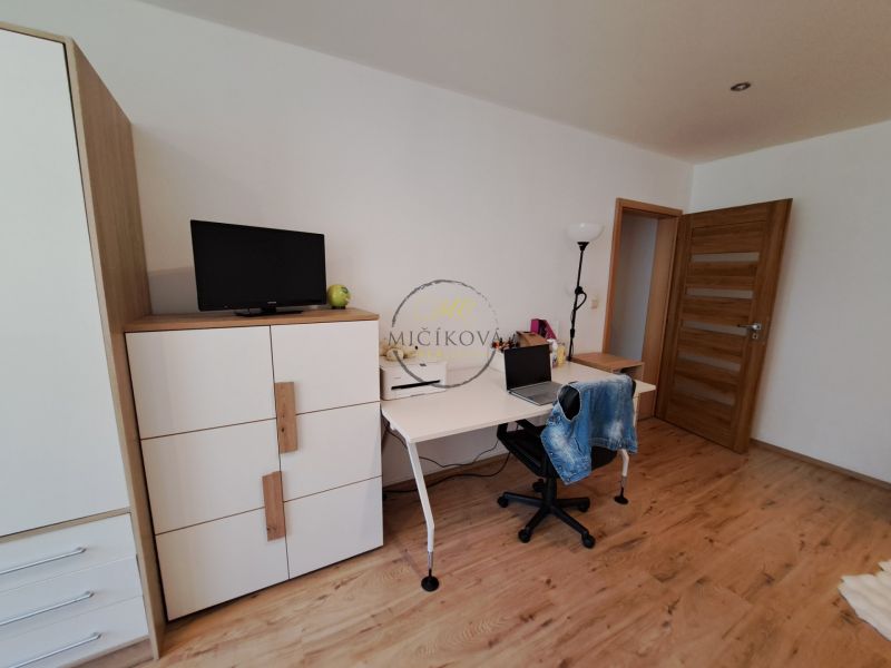 A room in a 3-room apartment with a wooden decor floor, a desk, and a wardrobe.