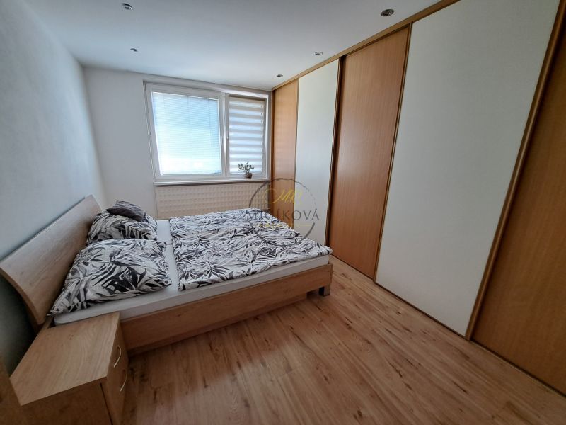 A bedroom in a 3-room apartment with a wooden decor floor and built-in wardrobes.