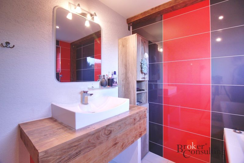 A bathroom in a family house with a sink, a mirror, and striking tiles.