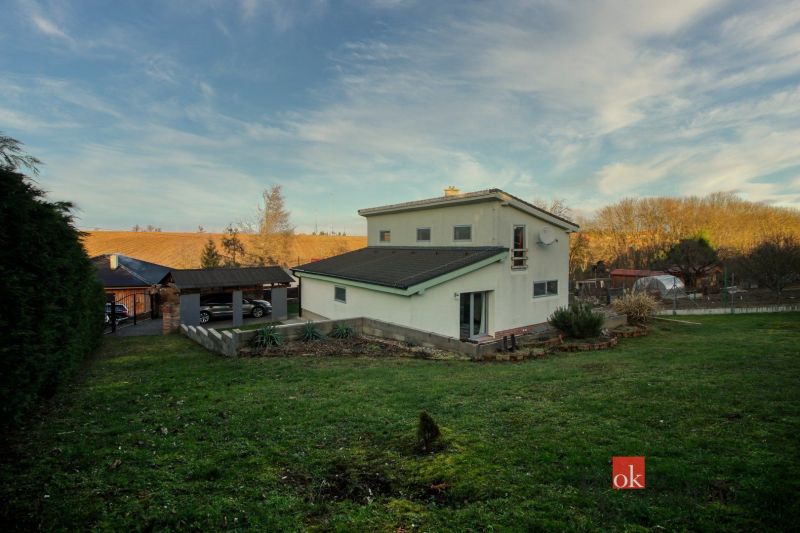 A family house in Suchá nad Parnou with a grassy garden and a gazebo at sunset.