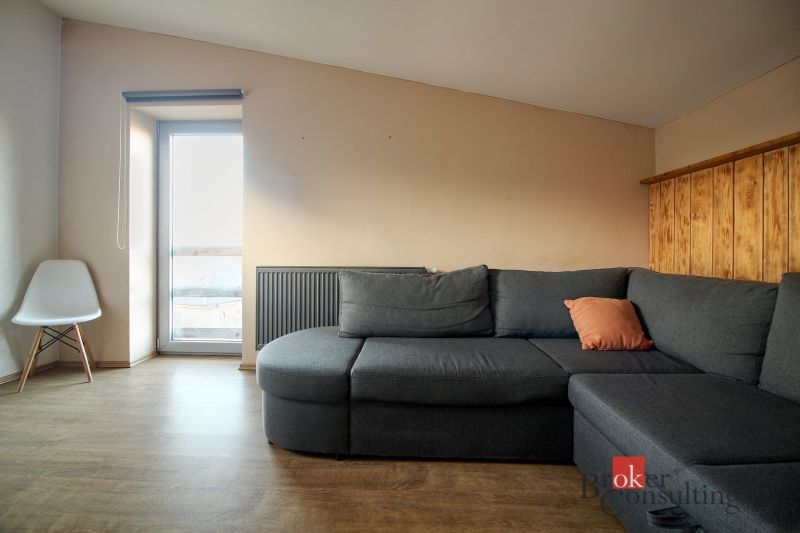 Living room with a dark gray sofa, armchair, and wood-patterned flooring in a family house.