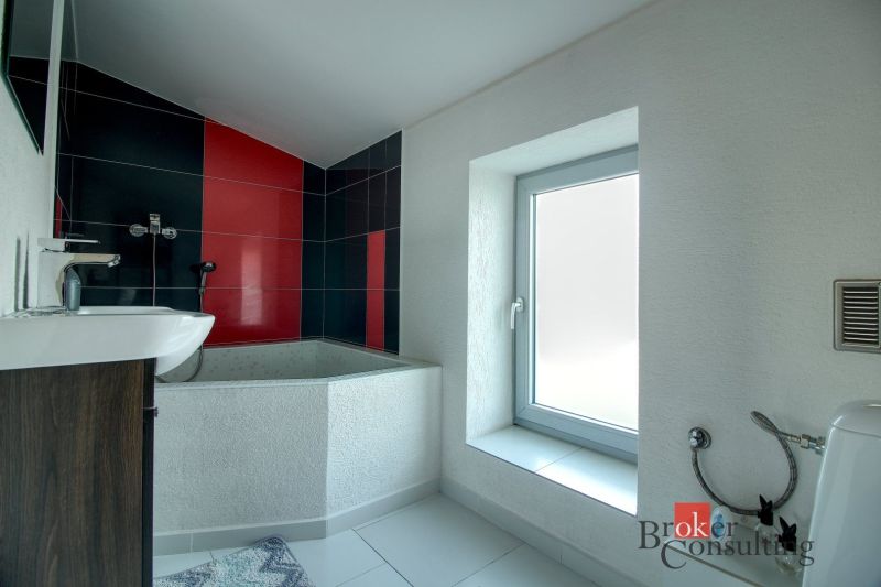 A bathroom in a family house with a corner bathtub and colorful tiles.
