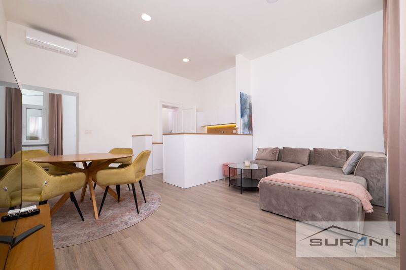 Living room in a two-room apartment with a wooden decor floor, yellow chairs, sofa.
