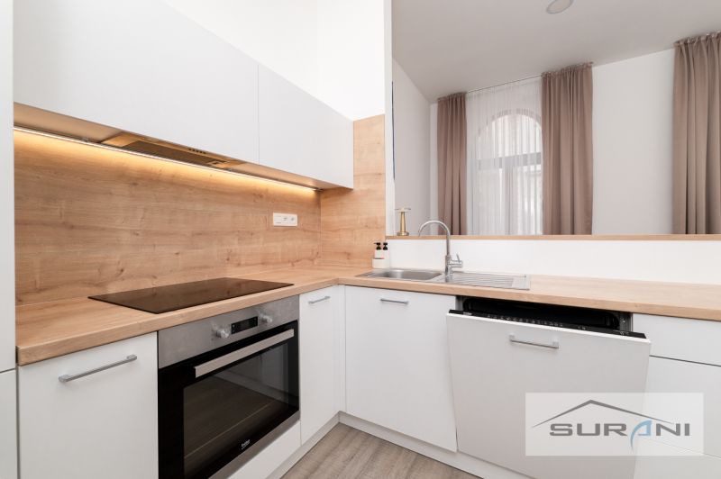 A kitchen in a 2-room apartment with a wooden decor floor and white cabinets.