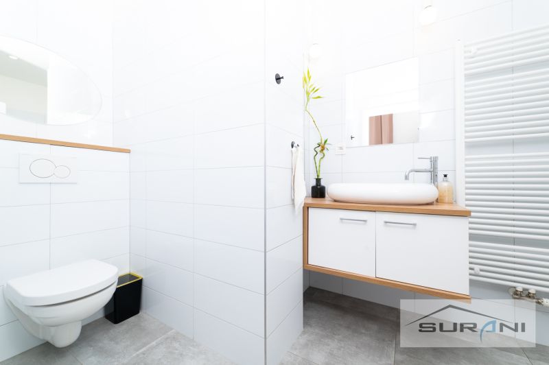 A bright bathroom with modern furniture, a sink, and a mirror in a two-room apartment.