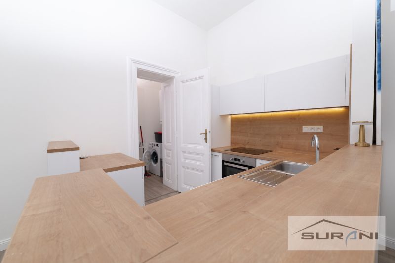 A kitchen in a 2-room apartment with a wood-patterned floor and built-in appliances.