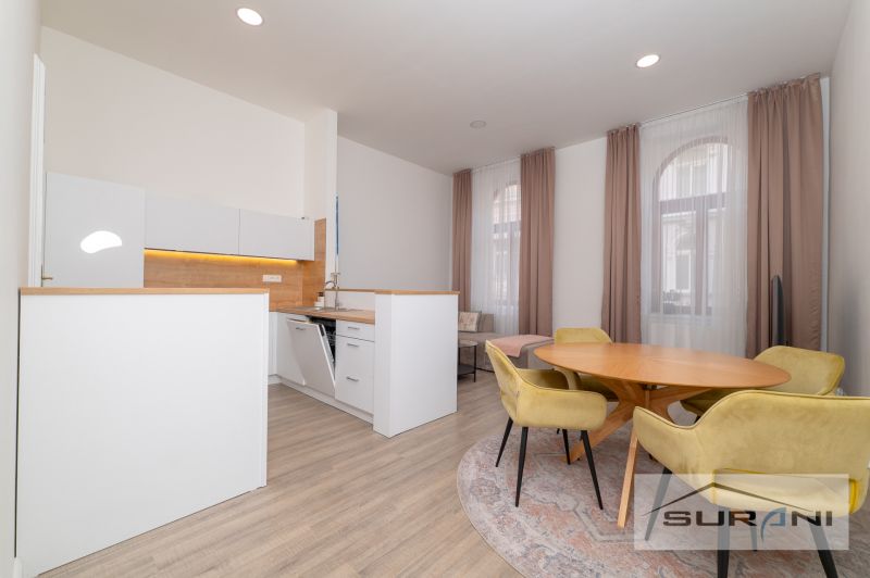 Interior of a 2-room apartment with a kitchen, dining table, and wooden decor flooring.