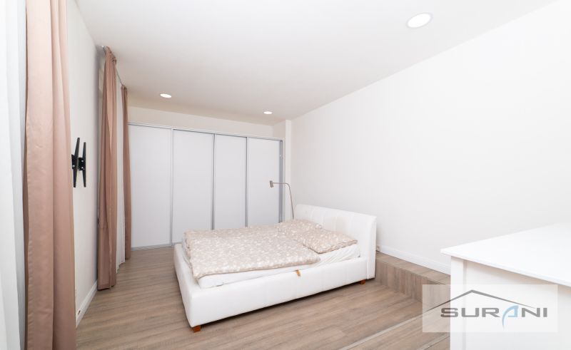 A bedroom with a white bed and a wooden decor floor in a 2-room apartment.