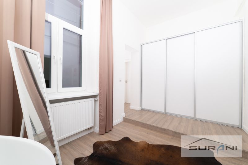 A bedroom with wood-patterned flooring, a mirror, and a large wardrobe.