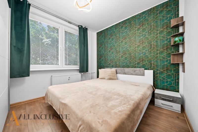 Bedroom in a 2-room apartment with a bed and a decorative green wall.