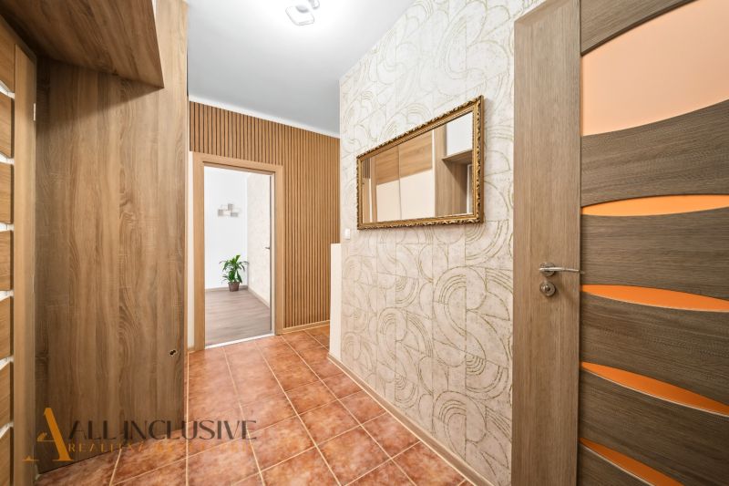 A hallway in a 2-room apartment with ceramic tiles, wooden doors, and a mirror on the wall.