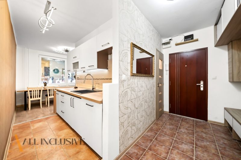 A kitchen in a 2-room apartment with white cabinets and tiled flooring.