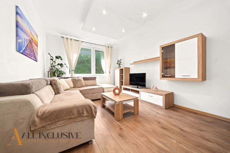 A bright living room with a comfortable sofa and wood-patterned flooring in a two-room apartment.