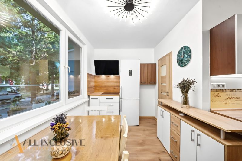 A kitchen in a 2-room apartment with a wooden decor floor and decorations on the table.