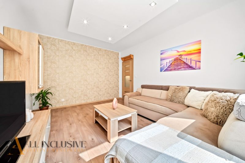 Living room with a sofa, a table, and a wooden decor floor in a 2-room apartment.