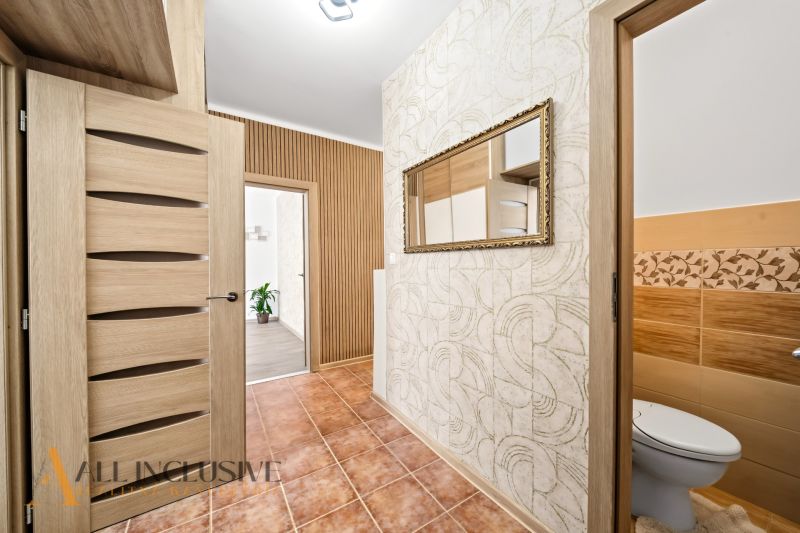 Interior of a 2-room apartment with tiles, a mirror, and doors with a wooden decor.