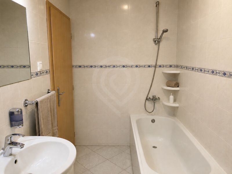A bathroom in a family house with a bathtub, shower, and a sink in the corner.