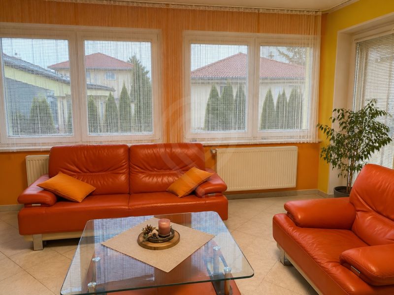 Living room with an orange sofa and large windows in a family house.