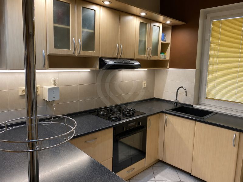A kitchen in a family house with a corner kitchen unit and a black sink.