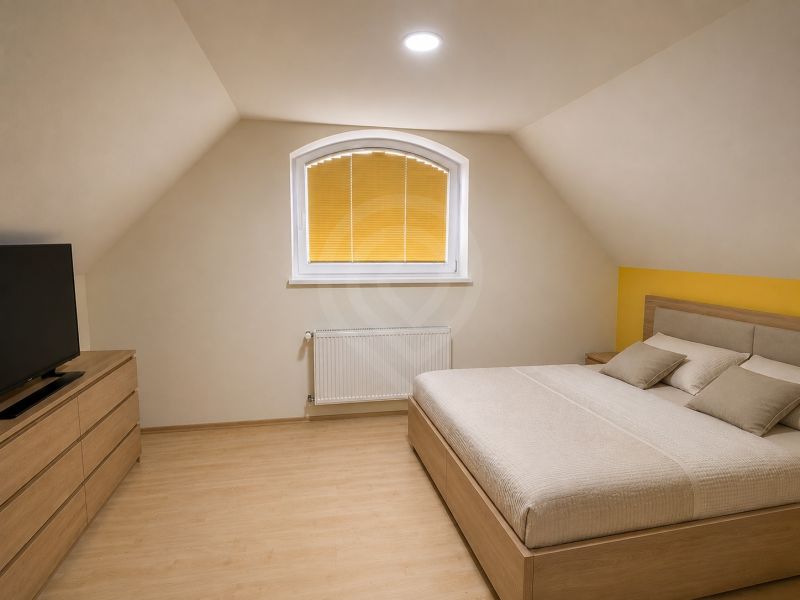 A bedroom in a family house with a wooden decor floor, a double bed, and a dresser.