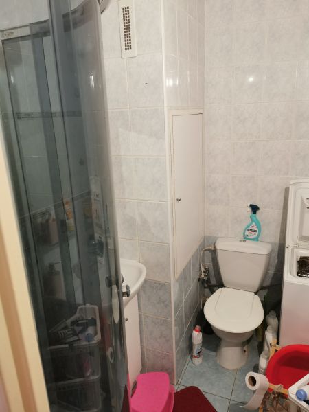 A bathroom in a studio apartment with a toilet, shower, and washing machine.