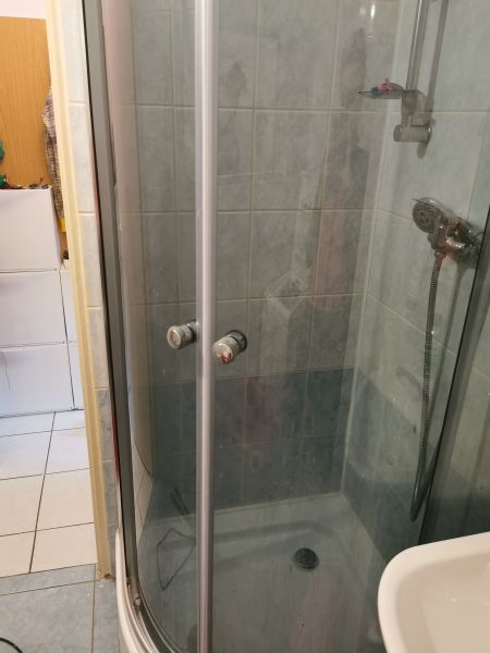 Bathroom in a studio apartment with a shower cabin and white tiles.