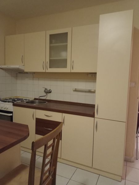 A kitchen in a one-room apartment with white cabinets and wooden decor.