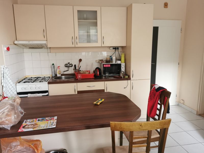 A kitchen in a studio apartment with a stove, wooden decor, and white cabinets.