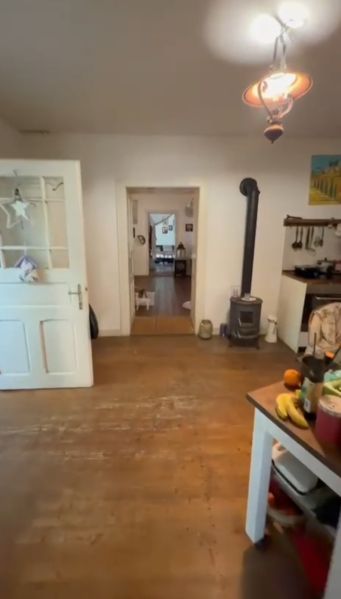 Interior of a family house with a fireplace, wooden decor flooring, and open doors.