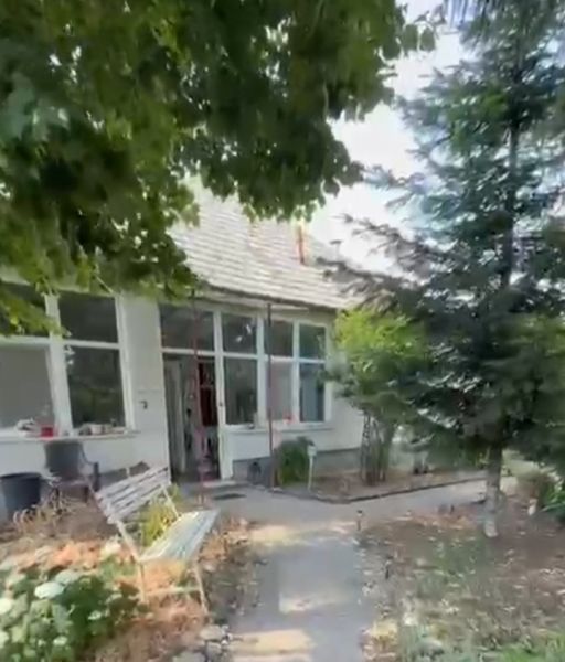 A family house in Imel with a bench, trees, and a garden path.