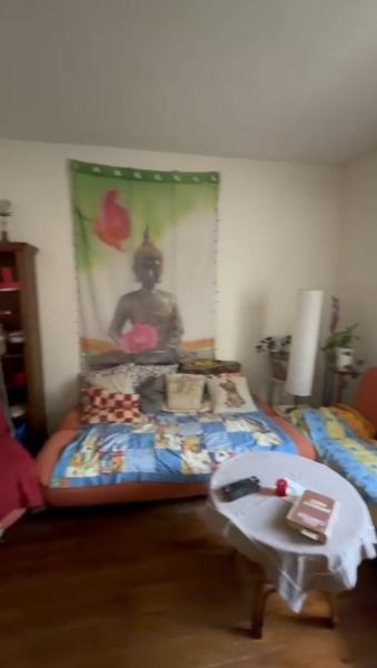 A room in a family house with a colorful blanket and a tapestry with Buddha on the wall.