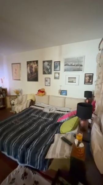 Bedroom in a family house with a couch, photos on the wall, and a bed with decorative pillows.