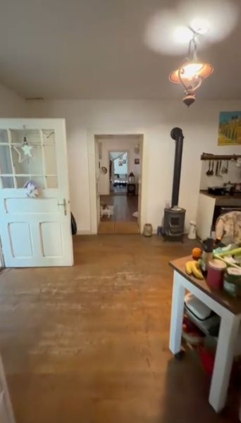 The interior of a family house with a wooden decor floor and a tiled stove.