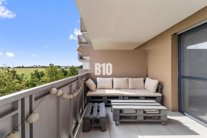 A balcony in a 4-room apartment with a view of the surroundings of Nitra and wooden seating made from pallets.