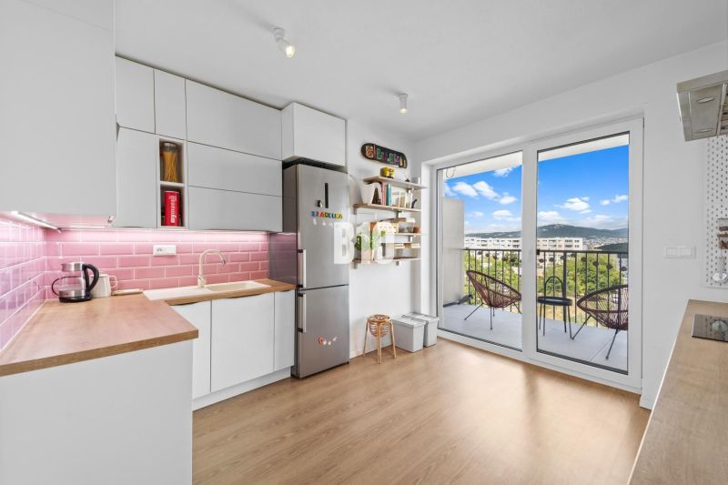 A kitchen in a 4-room apartment with a balcony and a wooden decor floor.