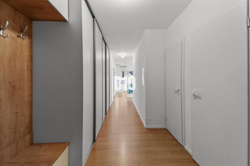 A hallway in a 4-room apartment with a wooden decor floor and storage space.