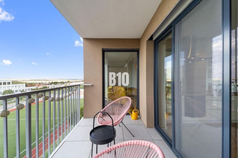The balcony of a 4-room apartment in Nitra with a view of the sports field and comfortable seating.