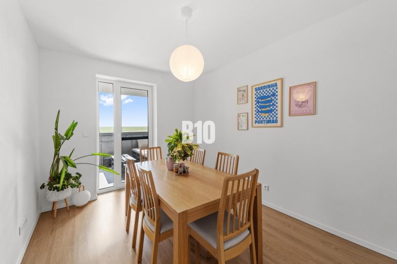 Dining room in a 4-room apartment with a wood-patterned floor and wall decorations.