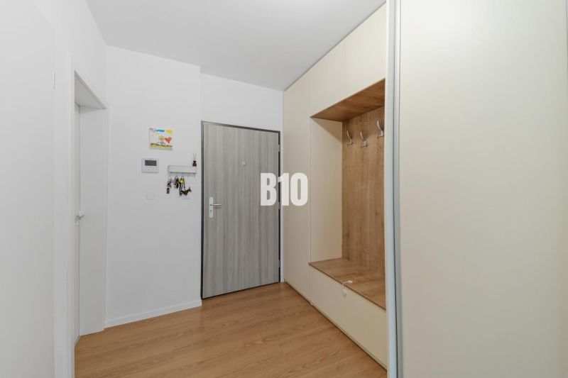 An entrance hall with light furniture and a wood-patterned floor in a 4-room apartment.