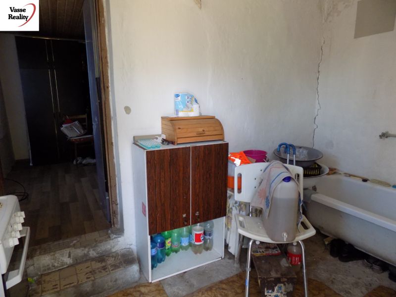A kitchen in a cottage with a storage cabinet and a bathtub, floor with wood decor.