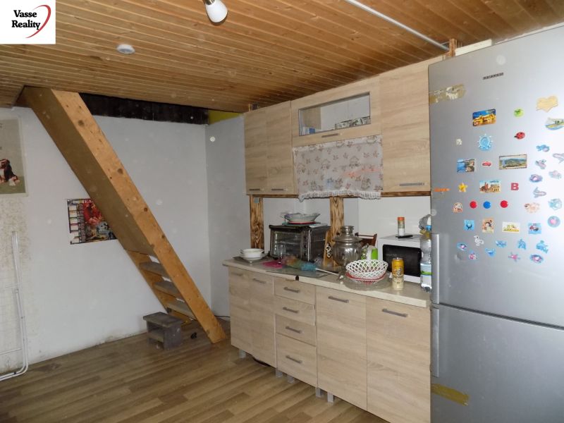 Interior of a cabin with a wooden ceiling, kitchen counter, and staircase, floor with wooden decor.