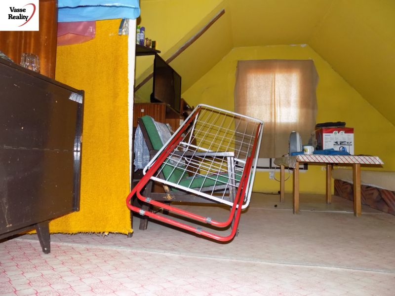 Interior of a cottage with a drying rack, table, and yellow walls. There is an attic and cabinets.