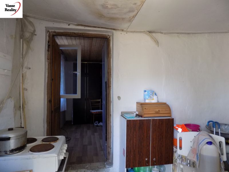 A kitchen in a cottage with an electric stove, a shelf, and a wooden decor floor.