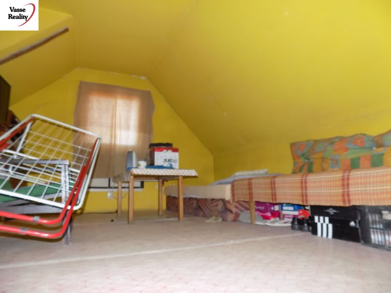 Yellow attic in a cottage with a bed and a folding chair.