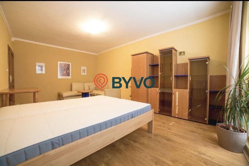 Bedroom in a 3-room apartment with a bed, wardrobe, and wooden decor flooring.