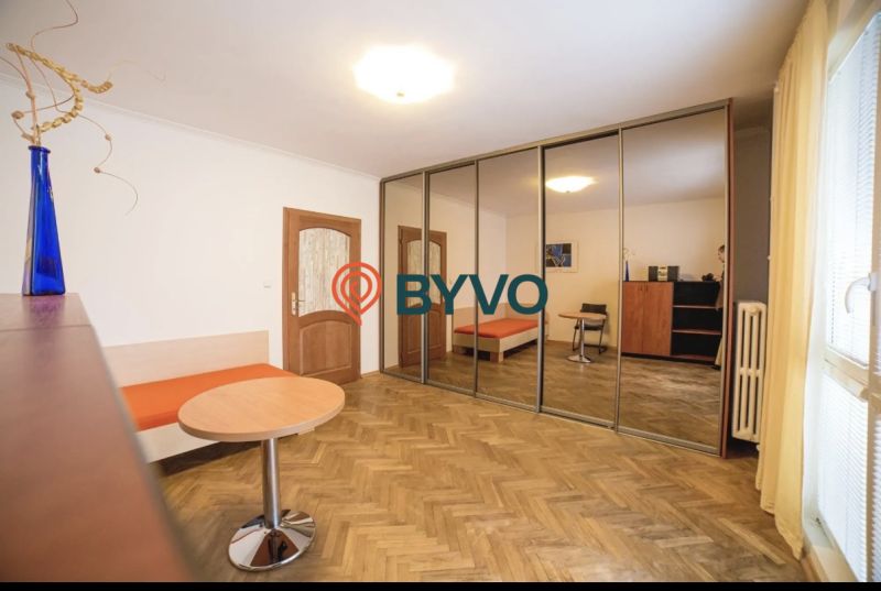 A room in a 3-room apartment with a wooden decor floor and a large mirrored wardrobe.